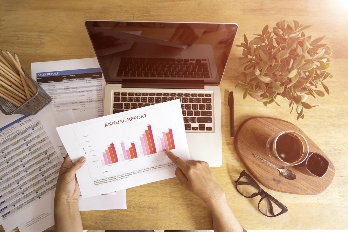 Young business woman pointing an annual report, working at office with a cup of coffee on wooden plate